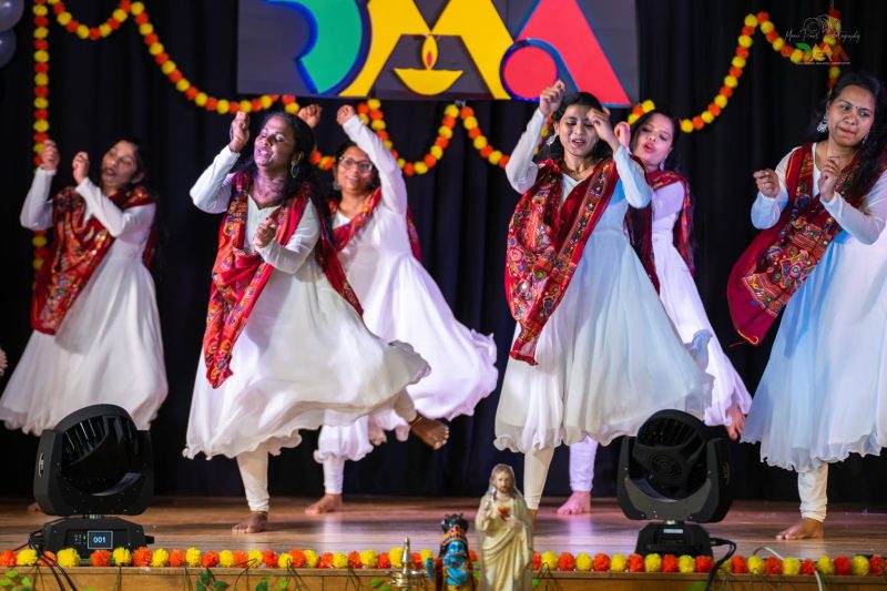 Dorchester Malayali Association performing at their Easter celebration. The dancers are mid movement with arms above heads.